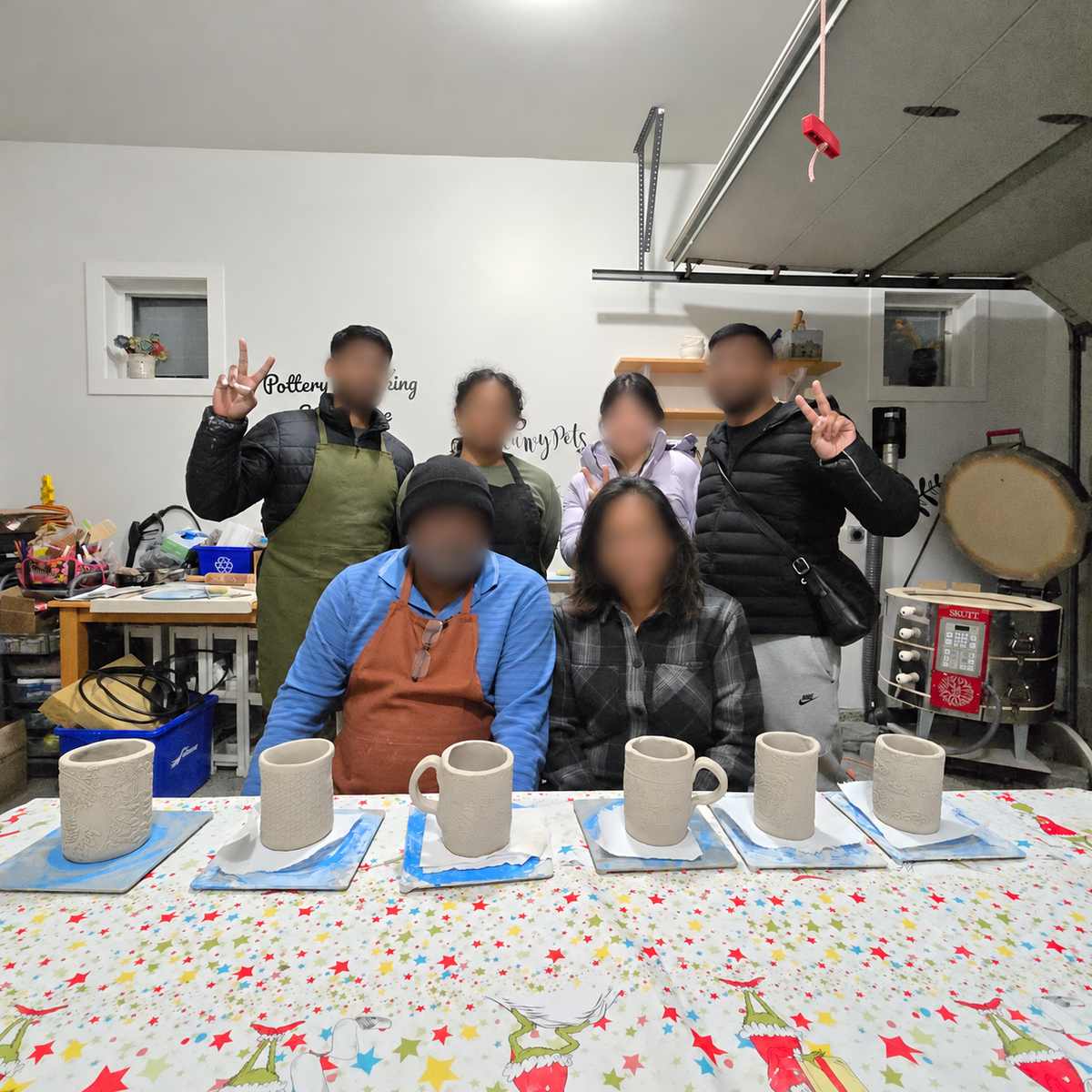 A family showing their handmade mugs after a pottery workshop, with faces blurred
