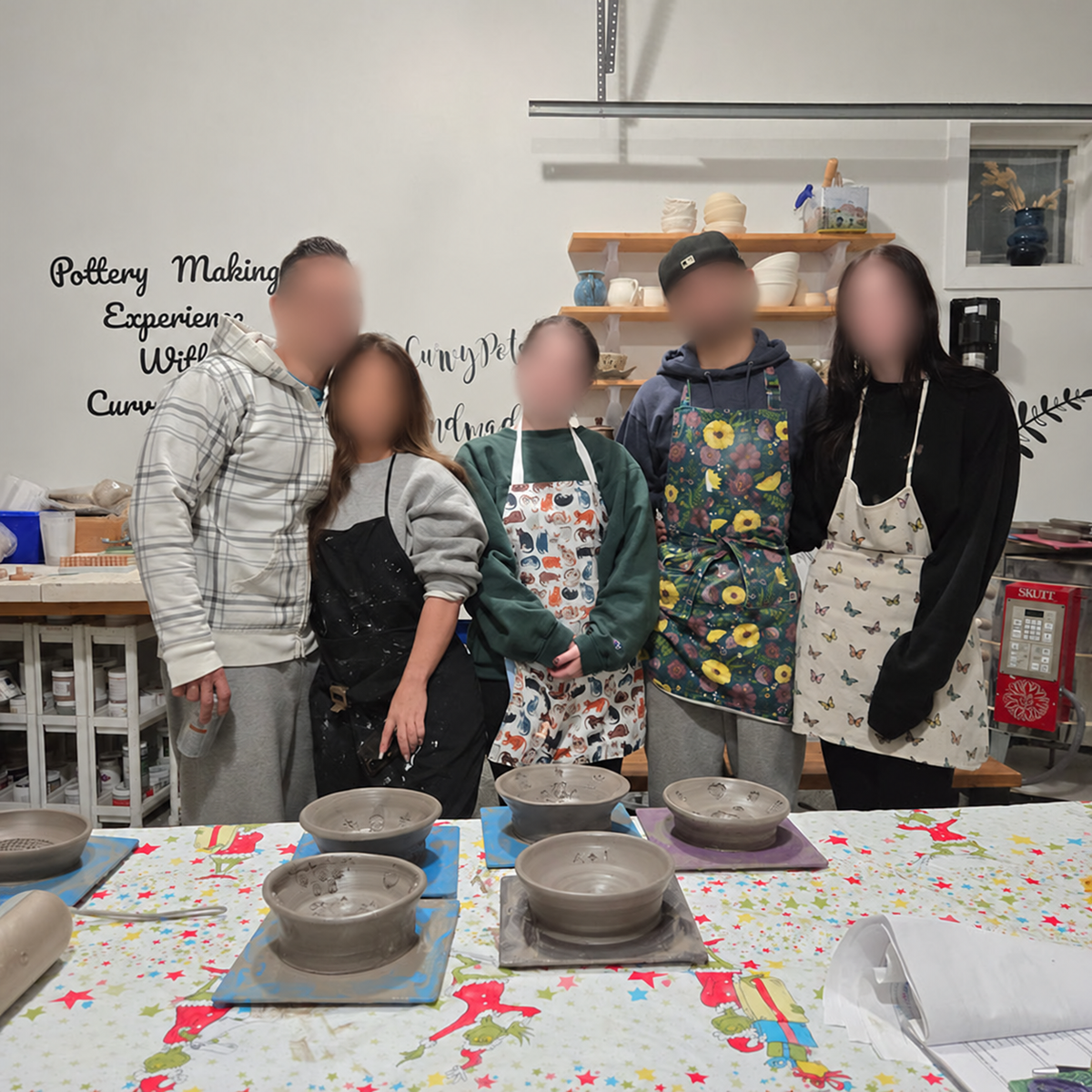 Five workshop participants with their handmade pottery bowls, with all faces blurred