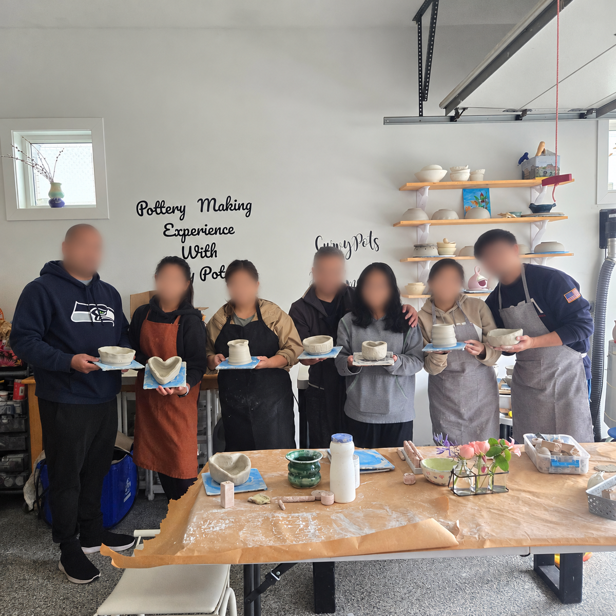 A group showing the pottery they made together in a beginner-friendly workshop, with faces blurred